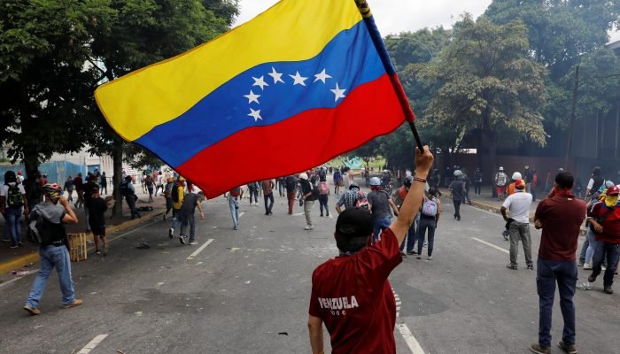 A demonstrator waves a Venezuela's flag while clashing with riot security forces during a rally against Venezuela's President Nicolas Maduro in Caracas, Venezuela June 5, 2017. REUTERS/Carlos Garcia Rawlins
